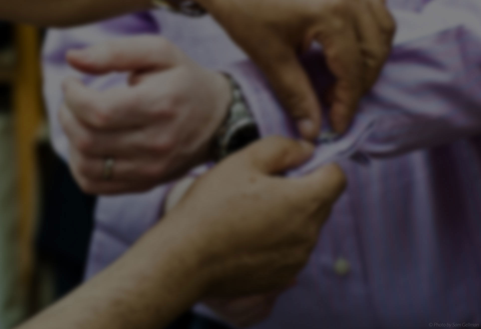 Tailor helping customer with shirt cuff button